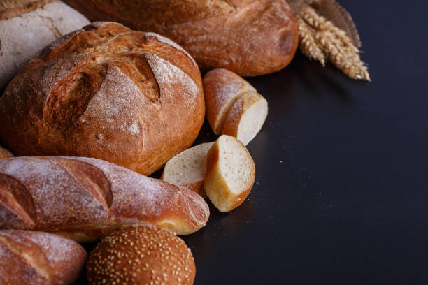 istock Bakery - gold rustic crusty loaves of bread and buns on black chalkboard background. 2158080372