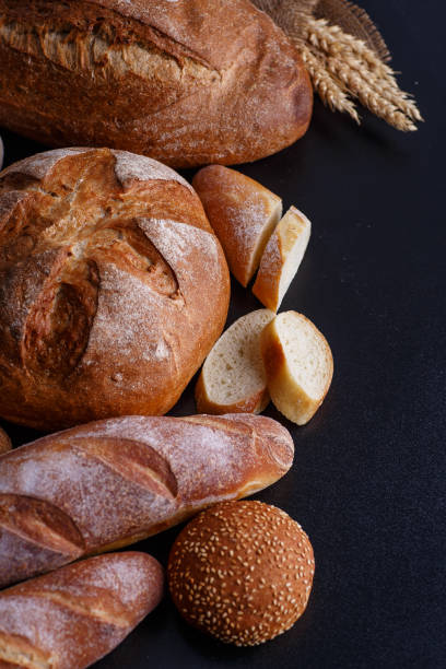 istock Bakery - gold rustic crusty loaves of bread and buns on black chalkboard background. 2158080376
