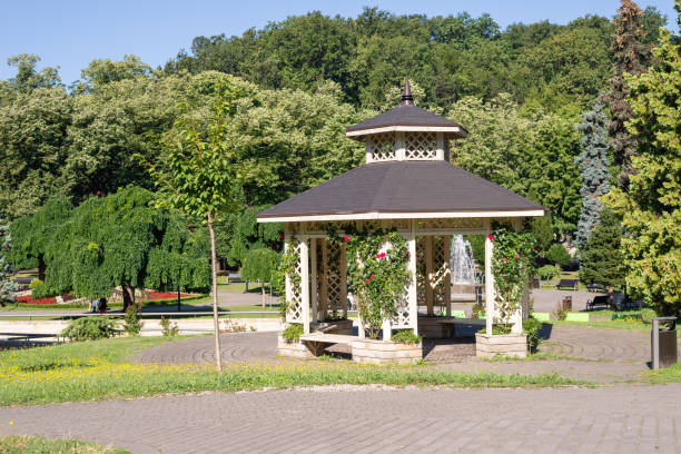Elegant gazebo surrounded with lush park trees in summertime