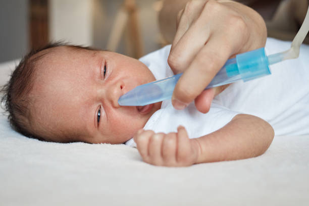istock Dedicated unrecognizable mom using suction bulb to clear her baby's mucus mother cleaning her sick infant's nose using a nasal sucker to help her baby breathe 2158083671