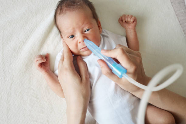 istock Tender anonymous mother treating her baby's flu with suction pump using aspirator to clean her child's nose using medical equipment to clear her infant's nasal congestion 2158083675