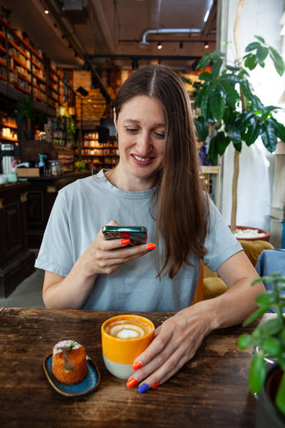 istock Woman Uses Smartphone While Enjoying Coffee and Pastry in a Cafe 2158084909