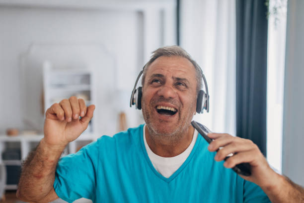 istock Senior laughing while holding mobile phone and headphones 2158085626