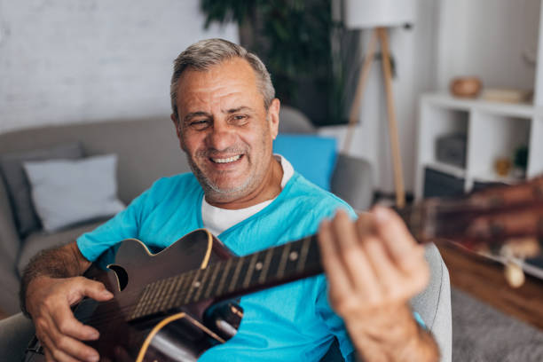 istock Smiling senior playing a guitar indoors 2158085727