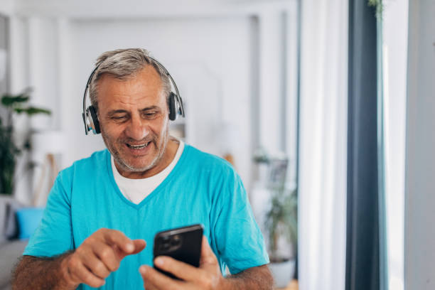 istock Smiling senior using smartphone with headphones 2158086954