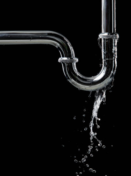 istock Drain leak water from pipe plumbing in bathroom as water clogged drop. Black background isolated. Leaking water from chromium stainless steel pipe under sink 2158087424