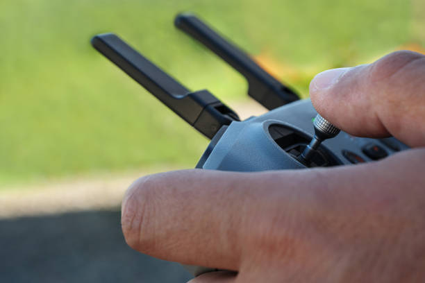 Close-up view of hands holding and maneuvering a drone remote control with a blurred green background.