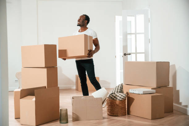 istock Happy black man is moving in his new home, holding box 2158091509