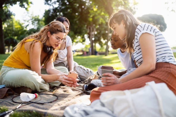 istock Multiracial female friends using mobile phone during picnic 2158092417