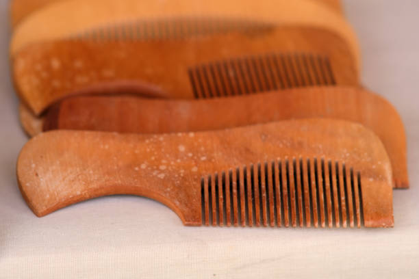 A row of wooden combs are lined up on a table. The combs are all different sizes and shapes, but they all have a similar texture and color. The scene gives off a rustic, natural vibe