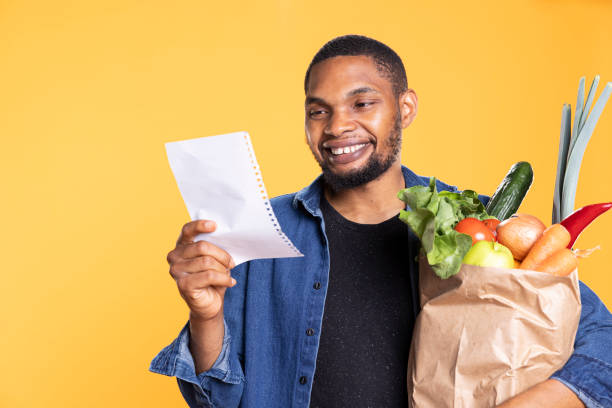 istock Young adult smiling while he verifies his shopping list on camera 2158099722