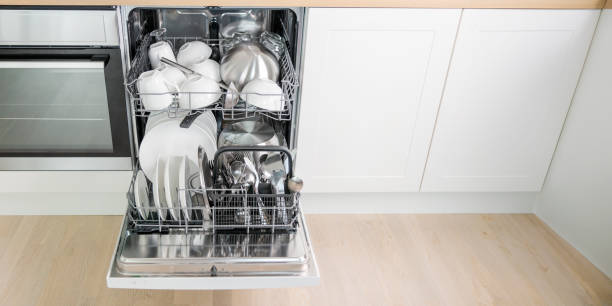 istock Open full built-in dishwasher machine with clean cutlery, dishes, plates in white modern kitchen. Front view banner 2158100097