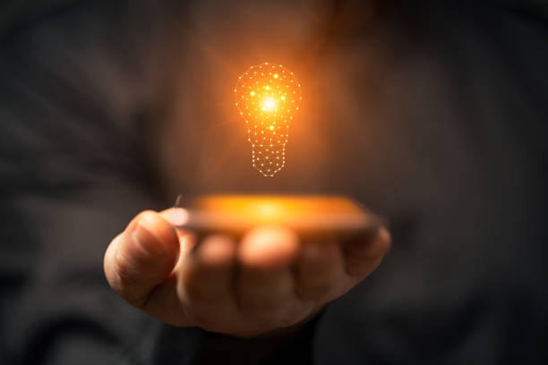istock Idea concept with hand holding smartphone with glowing light bulb 2158100334