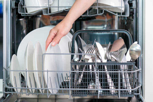 istock Female hand unloading dishwasher with tableware. Kitchen appliances, lifestyle view. Woman takes a plate from the dishwasher. Concept of modern technologies in the kitchen 2158100413