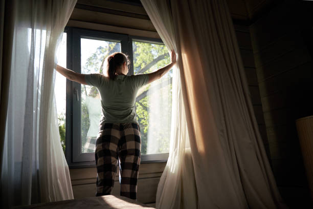istock Woman Opening Curtains to Bright Morning Sunlight 2158101903