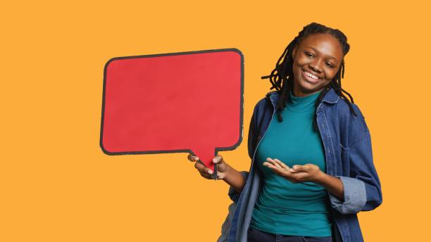 istock Smiling woman holding red speech bubble sign, studio background 2158102149