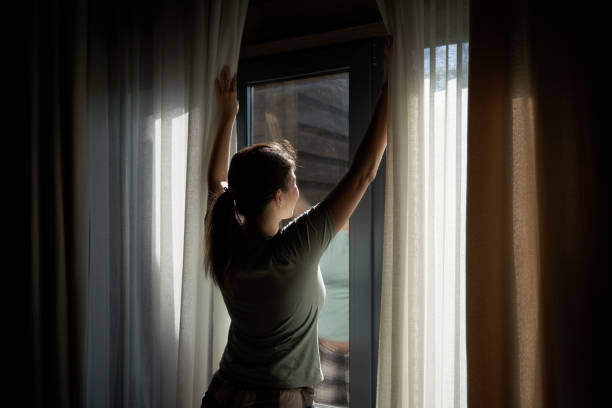 istock Woman Opening Curtains to Let in Morning Light 2158102282