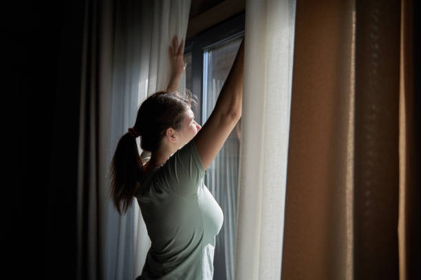 istock Woman Opening Curtains to Morning Sunlight 2158102391