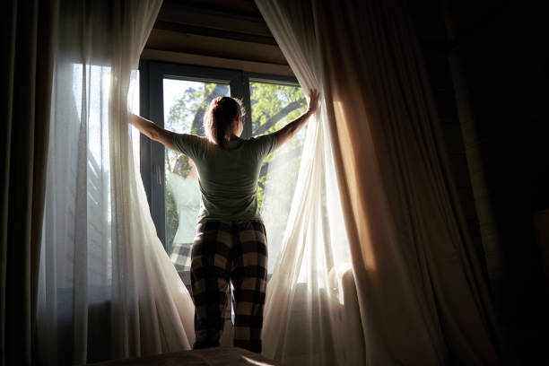 istock Woman Drawing Curtains to Bright Morning Sunlight 2158102413