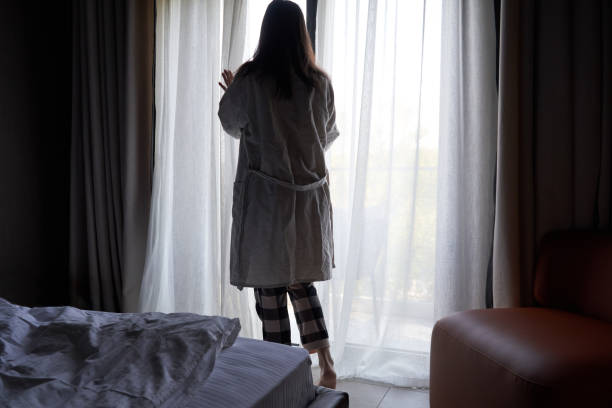 istock Woman in Robe Opening Curtains to Morning Light 2158102436