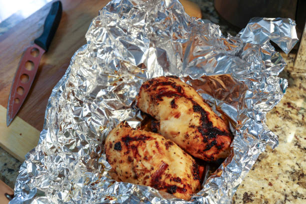 Freshly grilled chicken breast resting in aluminum foil