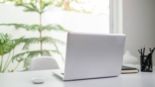 istock Laptop computer on white table near window with view of garden. 2158103645