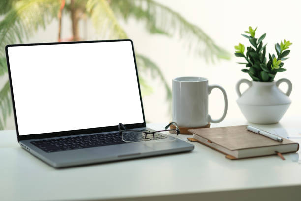 istock Laptop computer with blank screen, notepad and cup of coffee on white working desk near window. 2158106256