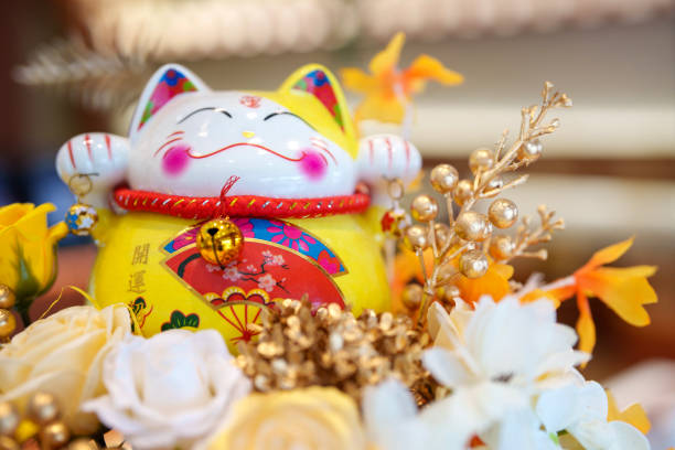 istock A cute yellow Maneki neko cat waving with paw close up 2158106433