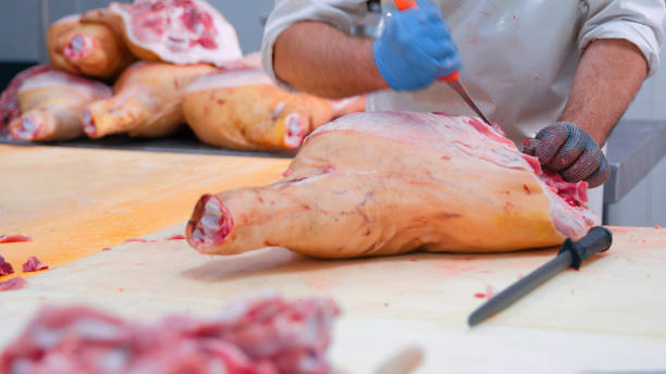 istock Butcher Cutting Large pork shank of Meat Slab in Processing Facility 2158108504