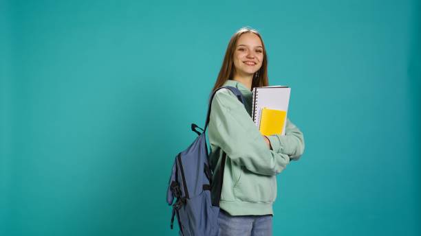 istock Portrait of smiling woman with backpack holding school notebook and notes 2158108926