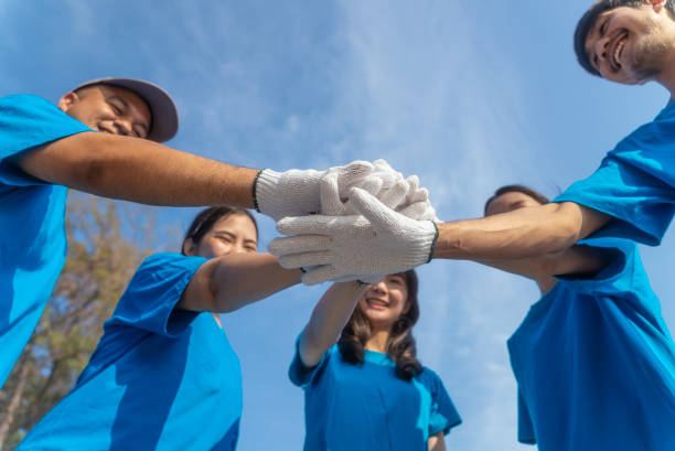 istock Plastic pollution and environmental problem concept. Happy asian diverse group of volunteers wearing blue t-shirt stacking hands together after cleaning plastic on the beach. 2158109970