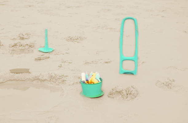 A shovel and a bucket on the beach waiting to be played with on a beautiful warm summer day