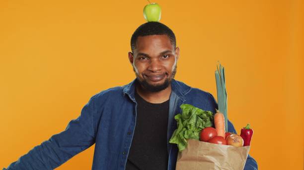 istock Playful vegan guy dancing with an apple placed on his head 2158114066
