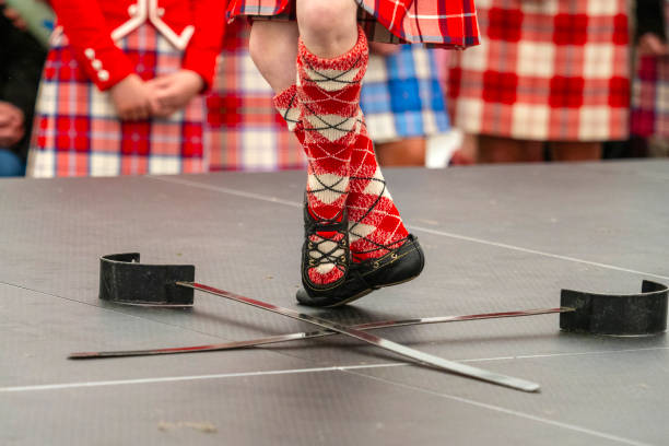 Oldmeldrum, Scotland, UK - June 15, 2024:  A Highland Dancer performing the Sword Dance at the Highland Games in Oldmeldrum, Scotland.  Highland games are a part of Scottish culture and a popular day out for both tourists and local people alike during the summer.