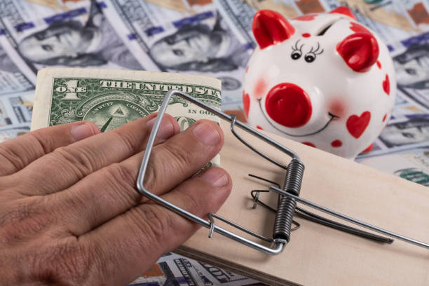 istock Man's fingers in a mousetrap and US dollars 2158115238