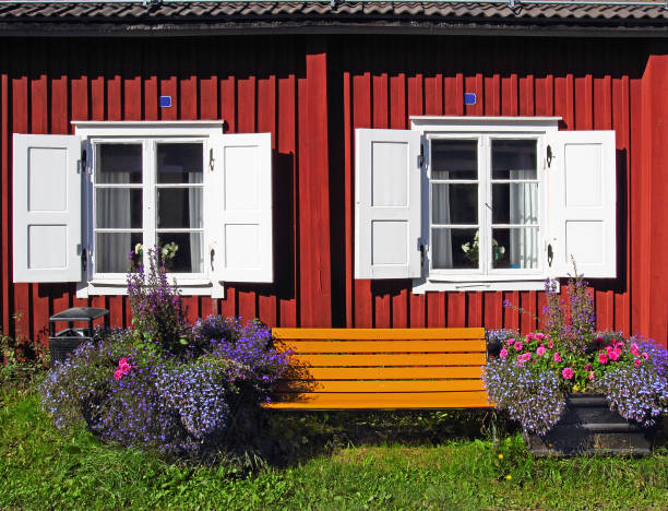 Colorful wooden horse toys displayed on a cottage window sill framed by green plants and rustic wood. The nostalgic detail evokes folk art, tradition, and countryside simplicity.