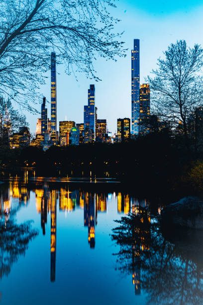 This is a view of the NYC Skyline at dusk reflected in the lake waters at Central Park in spring.