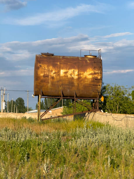 A weathered and rusted barrel sits quietly in a field of dry and yellowed grass