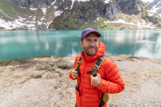 istock Man Hiking Alongside a Serene Mountain Lake 2158118550