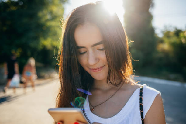 istock A woman is looking at her cell phone while walking down the street 2158119523