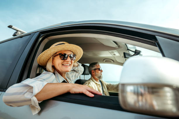 istock Senior woman leaning through car window while enjoying ride with her husband 2158120441