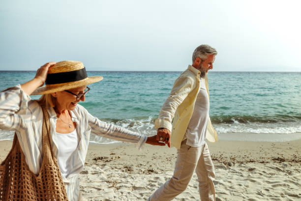 istock Senior couple holding hands while enjoying sunny day on a beach 2158120486