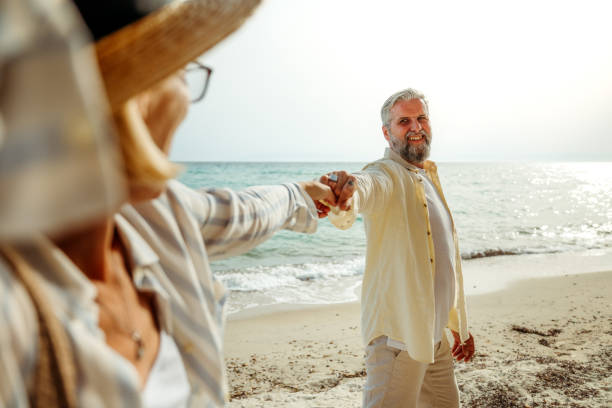 istock Senior couple holding hands while enjoying sunny day on a beach 2158120494