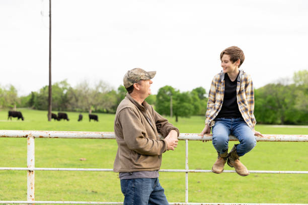 istock Dad talks to son sitting on pasture fence 2158124160