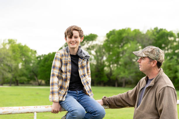 istock While talking to dad at fence, boy looks to camera 2158124195