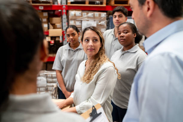 istock Group of warehouse workers talking in a staff meeting 2158124303