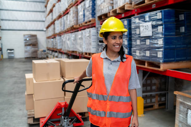 istock Woman moving boxes at a distribution warehouse using a pallet jack 2158124324