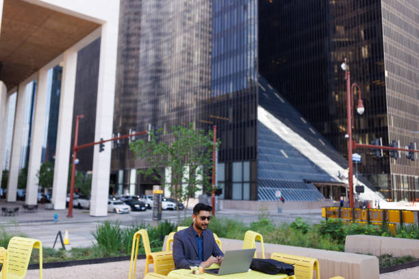 istock Man working on a laptop while sitting outdoors in the city 2158125169