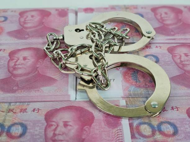 Handcuffs Resting on Stack of Chinese Yuan Banknotes