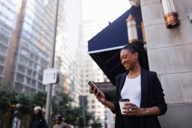 istock Smiling businesswoman texting with someone while drinking coffee outdoors 2158128767